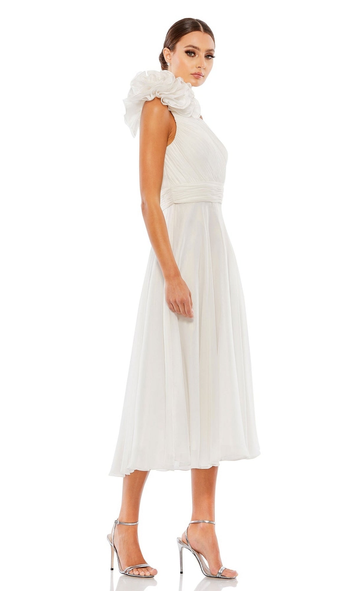 A woman models the Mac Duggal 49491 knee-length white party dress with a one-shoulder ruffle detail and silver high heels, posed against a white background.